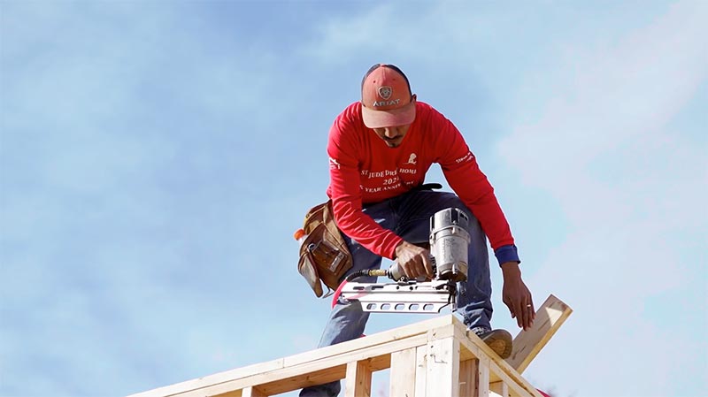 Worker with nailgun on building frame