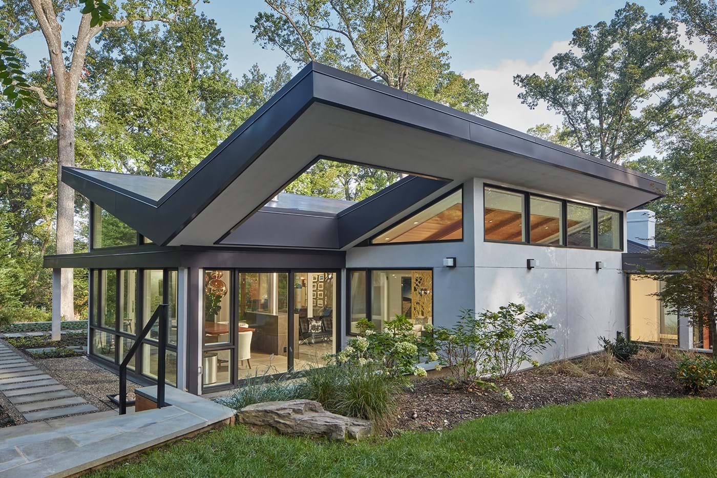 Modern gray house with inverted slanted roof set in a wooded area