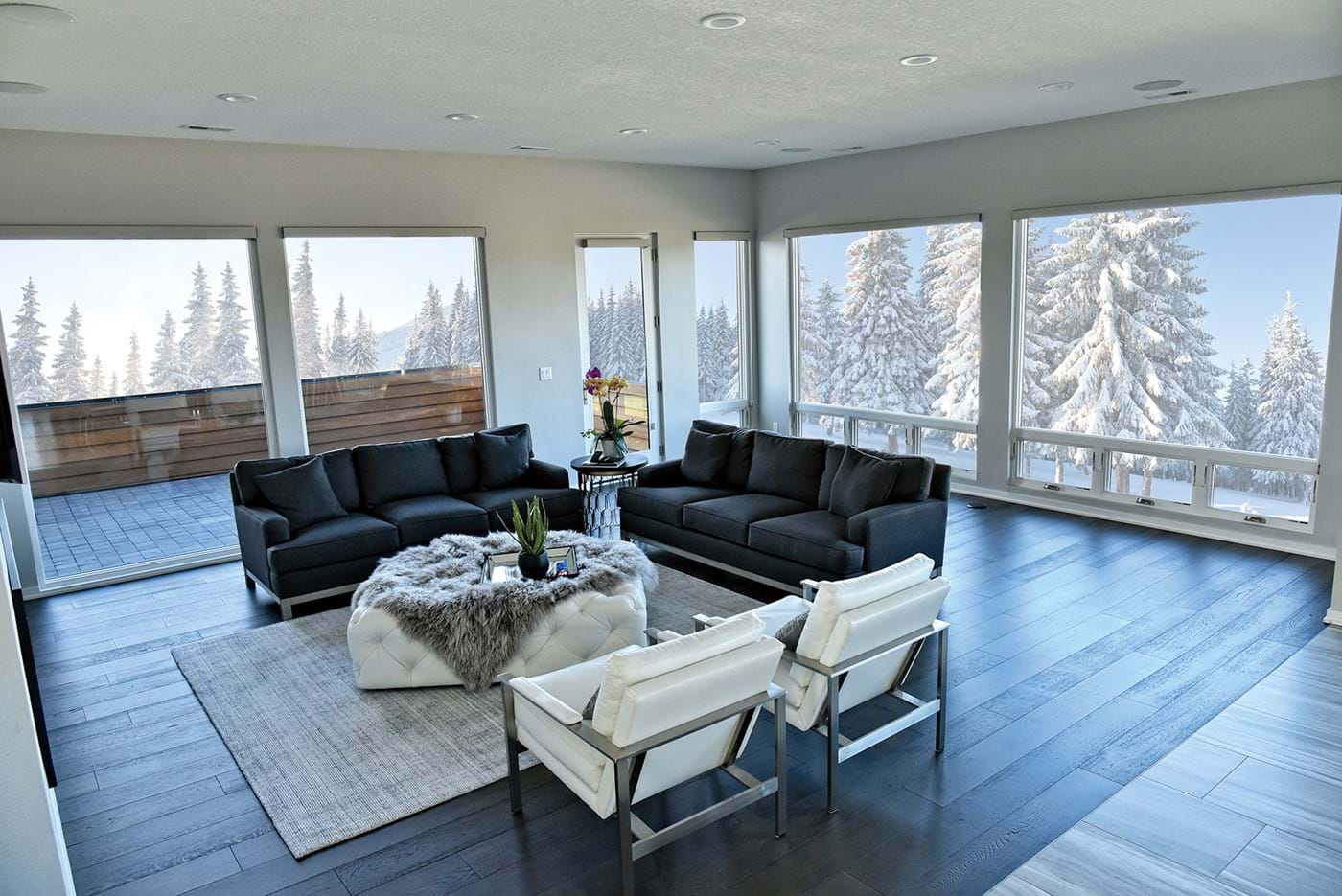 Living room seating arrangement surrounded by windows looking out to snow-covered landscape view